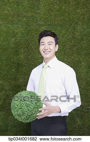 man holding a sphere covered with grass View Large Photo Image Stock Image - man holding a sphere covered with grass. Fotosearch