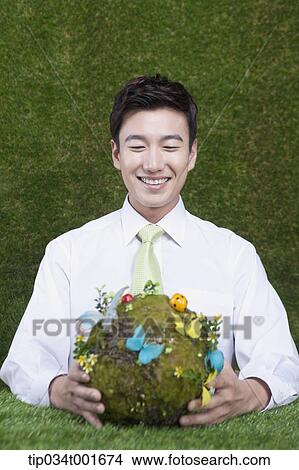Picture - man holding a sphere covered with colorful butterflies . Fotosearch