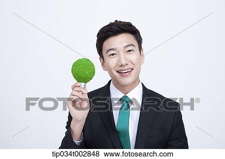 Stock Photo - man holding and a green bulb. Fotosearch