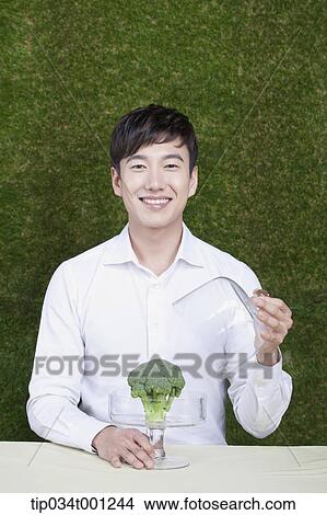 Picture - man opening the broccoli box. Fotosearch