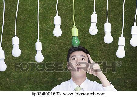 Stock Image - man pointing out one the bulbs hanging on the ceiling. Fotosearch