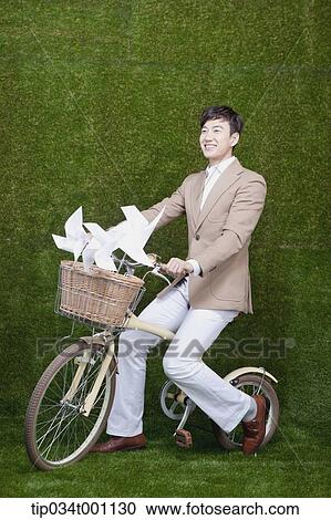 Stock Image - man riding a bike with pinwheel. Fotosearch