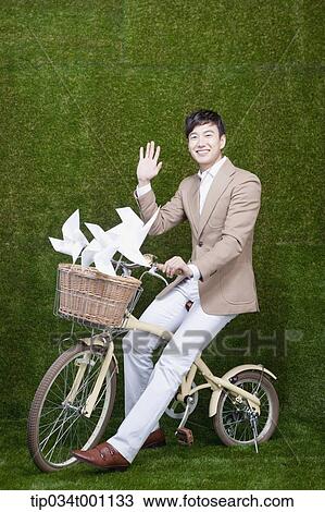 Stock Image - man riding a bike with pinwheel. Fotosearch