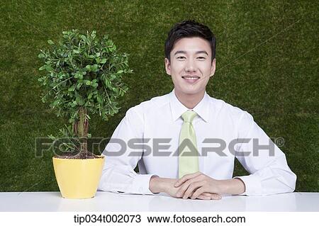 Stock Image - man sitting next to the tree pot. Fotosearch
