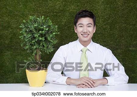 Stock Photo - man sitting next to the tree pot. Fotosearch