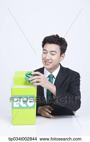 Picture - man throwing away trash into eco box. Fotosearch