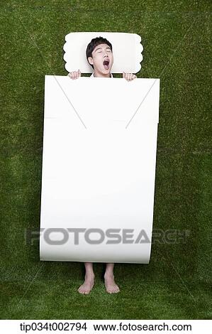 Picture - man yawning in the paper bedding. Fotosearch