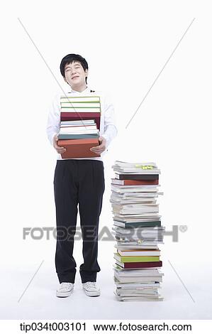 schoolboy holding books next to a stack of books View Large Photo Image Stock Image - schoolboy holding books next to a stack of books. Fotosearch