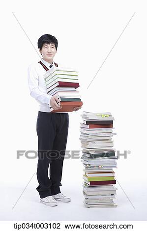 Stock Image - schoolboy holding books next to a stack of books. Fotosearch