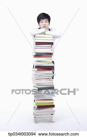 Picture - schoolboy standing behind a stack of books. Fotosearch