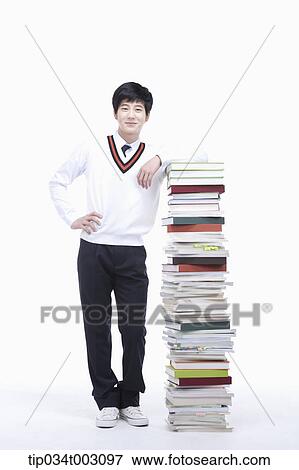 Stock Photo - schoolboy standing next to a stack of books. Fotosearch