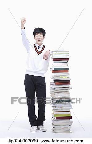 Stock Photo - schoolboy standing next to a stack of books. Fotosearch