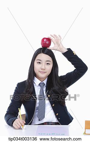 Stock Photograph - schoolgirl holding a red apple on her head. Fotosearch