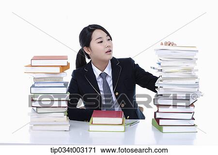 Stock Image - schoolgirl looking at piles of books . Fotosearch
