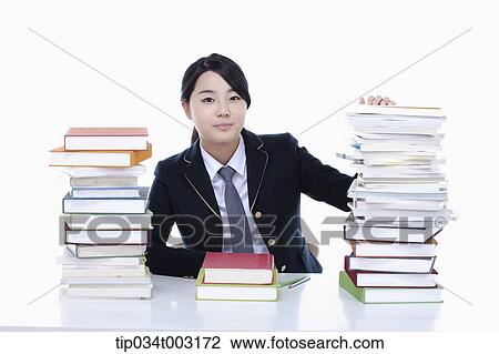 Stock Image - schoolgirl looking at piles of books . Fotosearch
