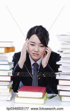 schoolgirl looking at piles of books and having a headache View Large Photo Image Stock Photo - schoolgirl looking at piles of books and having a headache. Fotosearch