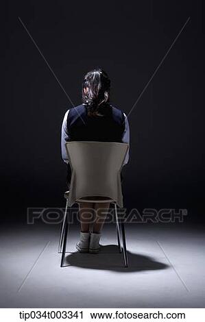 schoolgirl sitting on the chair in a dark room View Large Photo Image Stock Image - schoolgirl sitting on the chair in a dark room. Fotosearch