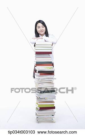 Stock Image - schoolgirl standing behind a stack of books. Fotosearch