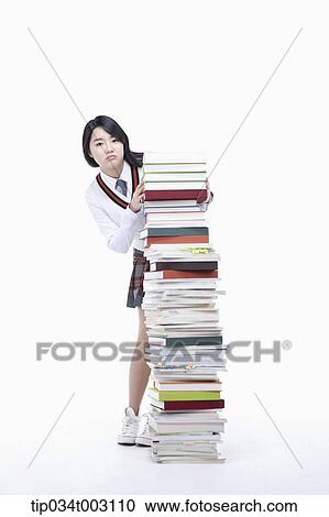 Stock Image - schoolgirl standing behind a stack of books. Fotosearch
