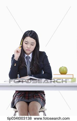 Stock Photo - schoolgirl studying hard on the desk. Fotosearch