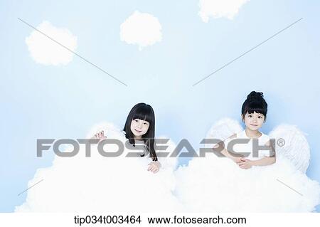 Picture - two little girls with looks of angels on the clouds. Fotosearch