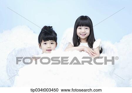 Stock Image - two little girls with looks of angels on the clouds. Fotosearch