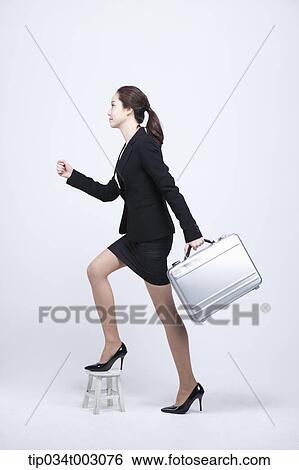 woman carrying a briefcase and stepping up the wooden chair View Large Photo Image Stock Photograph - woman carrying a briefcase and stepping up the wooden chair . Fotosearch