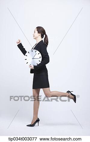 Stock Photo - woman carrying a clock and running. Fotosearch