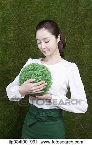 woman holding a sphere covered with grass View Large Photo Image Stock Image - woman holding a sphere covered with grass. Fotosearch