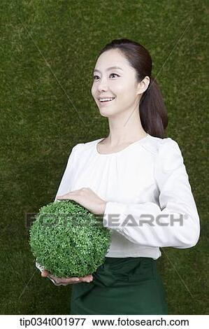 woman holding a sphere covered with grass View Large Photo Image Stock Photo - woman holding a sphere covered with grass. Fotosearch