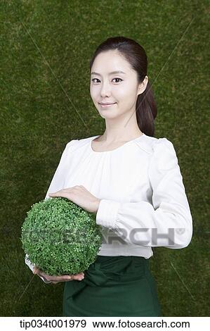 woman holding a sphere covered with grass View Large Photo Image Stock Photo - woman holding a sphere covered with grass. Fotosearch