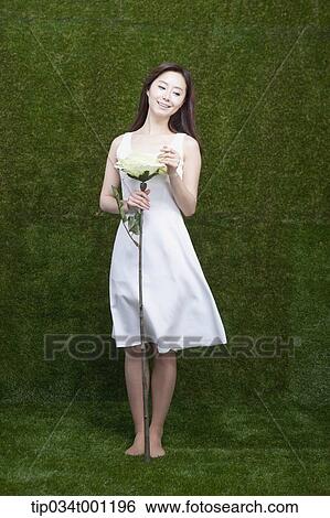Stock Photograph - woman holding flower in her bare feet. Fotosearch