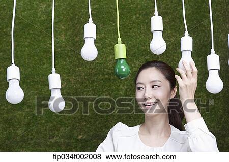 Stock Photo - woman holding one the bulbs hanging on the ceiling. Fotosearch