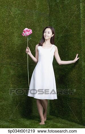 Stock Photo - woman holding pink flower in her bare feet. Fotosearch