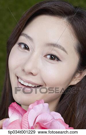 Stock Photo - woman holding pink flower with smile. Fotosearch