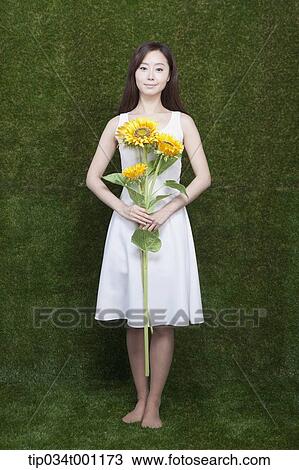 Stock Image - woman holding sunflower in her bare feet. Fotosearch