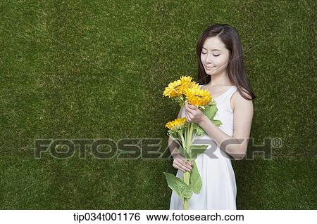 Stock Photograph - woman holding sunflower in her bare feet. Fotosearch