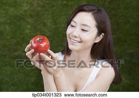 Stock Image - woman holding tomatoes on her hands . Fotosearch