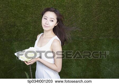 Stock Image - woman holding white flower. Fotosearch