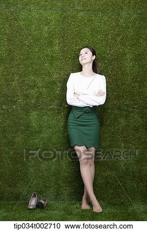 Stock Image - woman leaning against the wall in her bare feet. Fotosearch