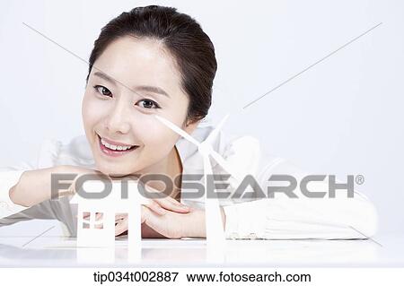 Stock Photo - woman looking at the white pinwheel and house model. Fotosearch