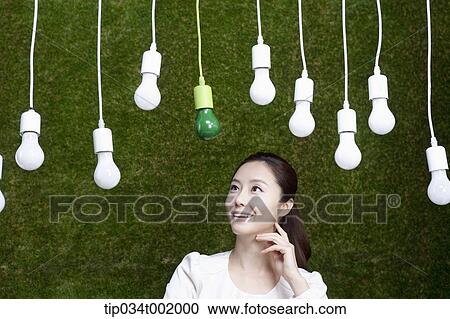 Stock Image - woman looking up the bulbs hanging on the ceiling . Fotosearch