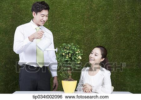 woman looking up the man watering the tree in the pot View Large Photo Image Stock Photograph - woman looking up the man watering the tree in the pot. Fotosearch
