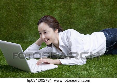 Picture - woman lying face and using laptop. Fotosearch