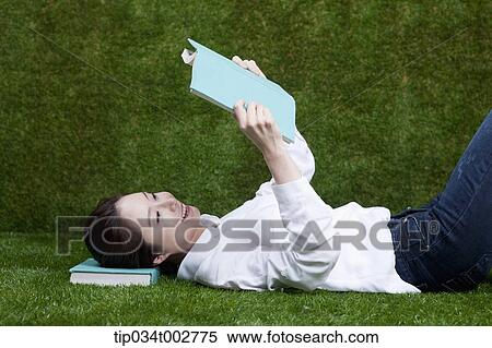 Stock Photography - woman reading a book with her head on a book. Fotosearch
