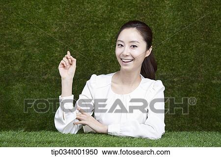 Stock Image - woman sitting and smiling with her chin propped on her hands. Fotosearch