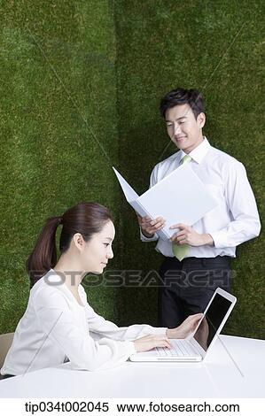 Stock Photography - woman using computer and man holding a folder. Fotosearch