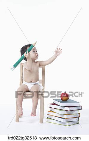 Stock Photo - A baby holding a pencil and piled books. Fotosearch