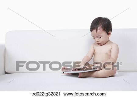 Stock Image - A baby looking at the tablet PC on the couch. Fotosearch