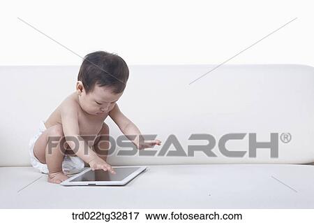 A baby looking at the tablet PC on the couch View Large Photo Image Stock Photo - A baby looking at the tablet PC on the couch. Fotosearch
